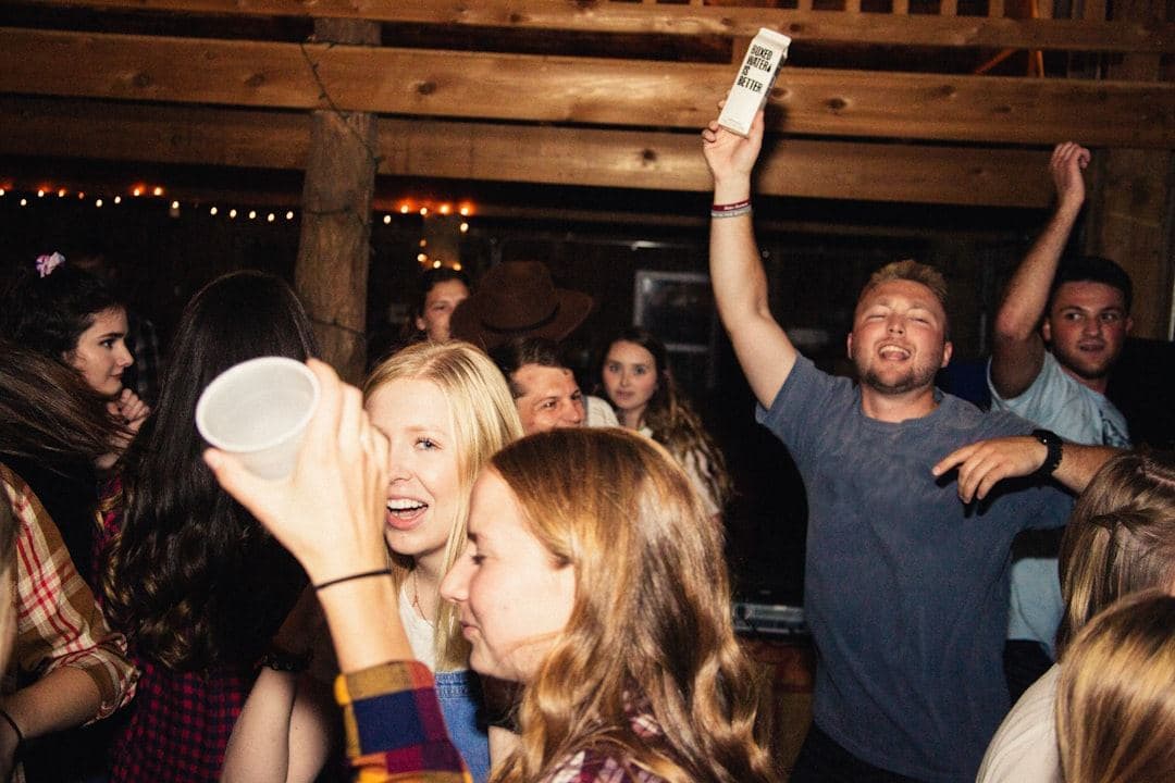 a crowded party lit up, hands and faces mid-celebration
